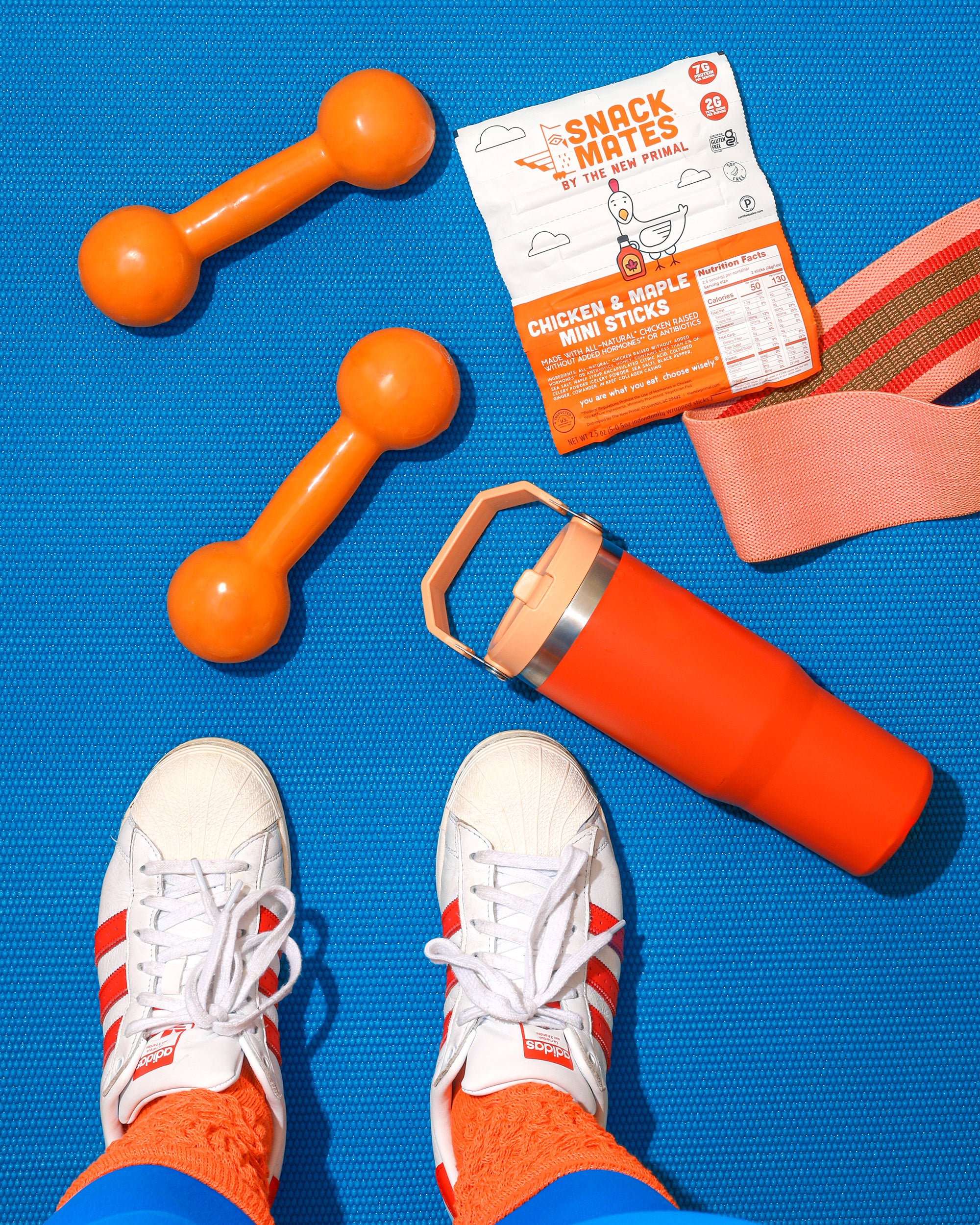 blue mat with orange buffalo chicken stick and orange stanley cup with white stan smiths on the bottom of the image