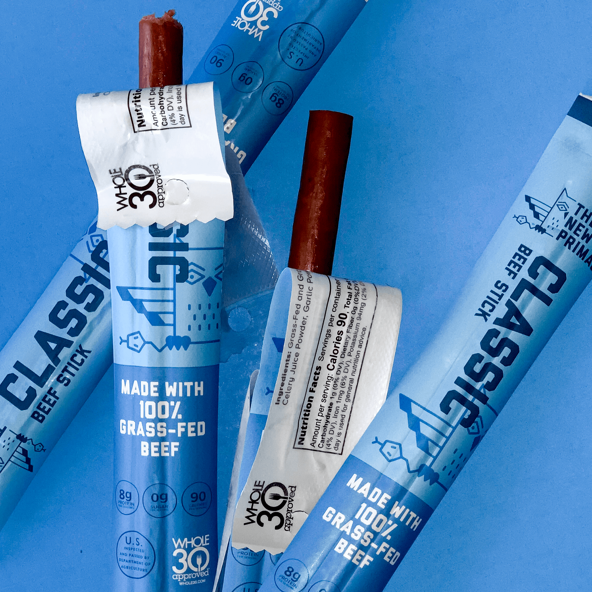 an image of two unwrapped and two wrapped Classic beef sticks against a blue background