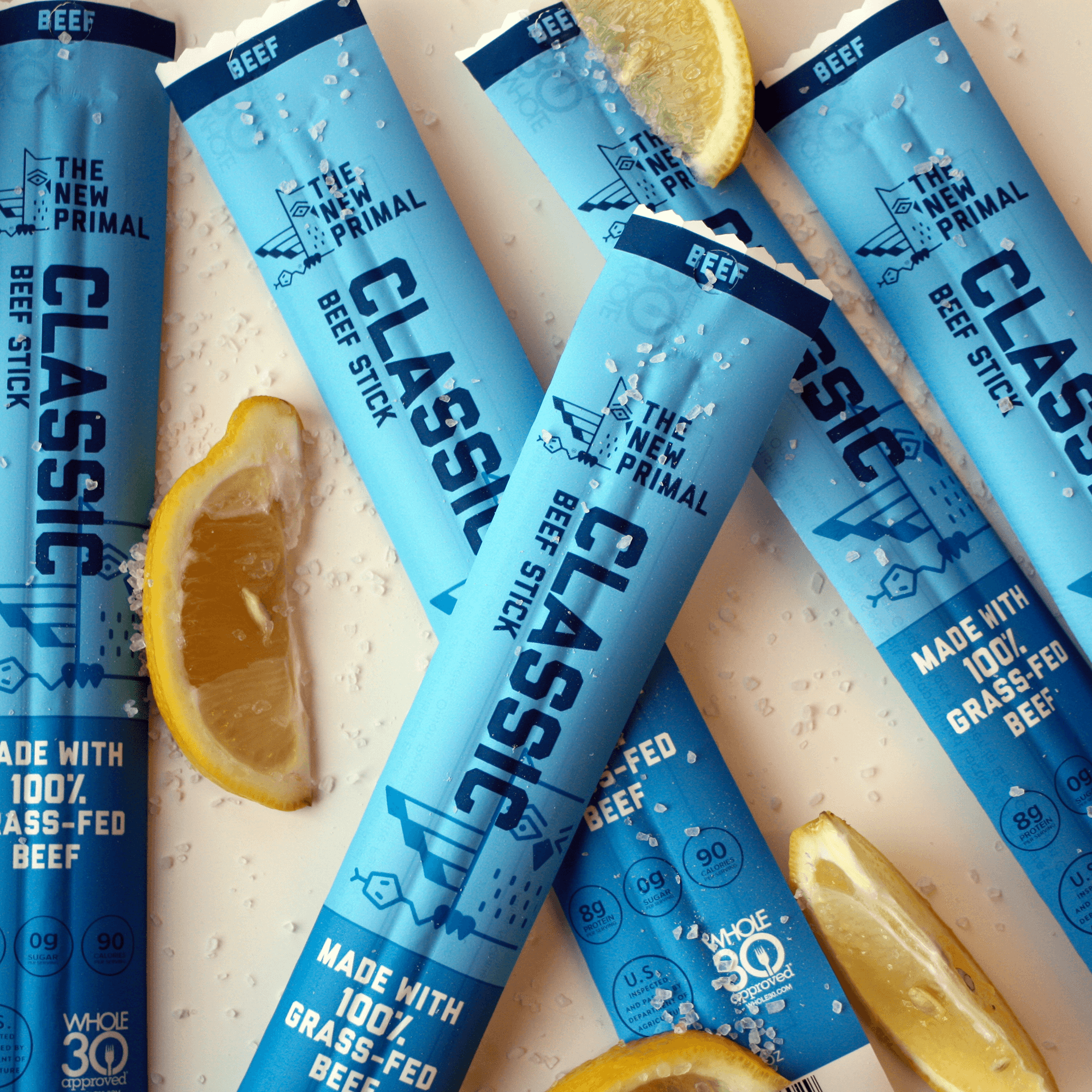 5 classic beef sticks on a white ground with lemon wedges and salt around them